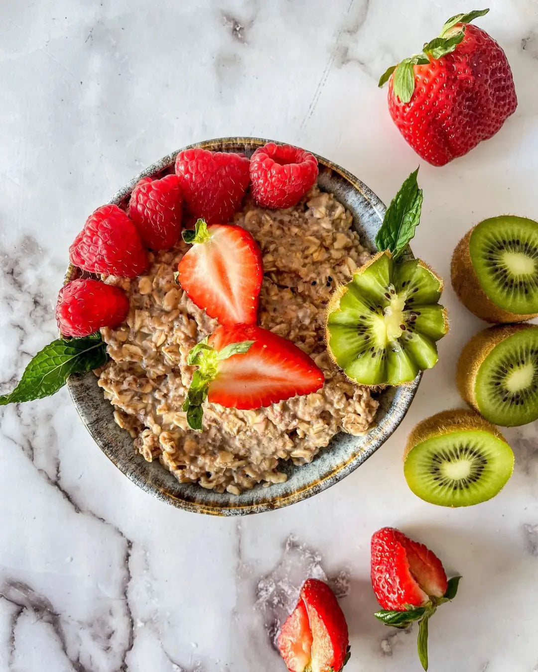 Raspberry instant oatmeal in a bowl with fresh strawberries and kiwis. 